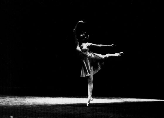 Blallet dancer on dark stage with spotlight